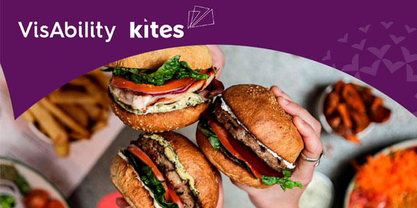 Three hands hold burgers. VisAbility and Kites logos 